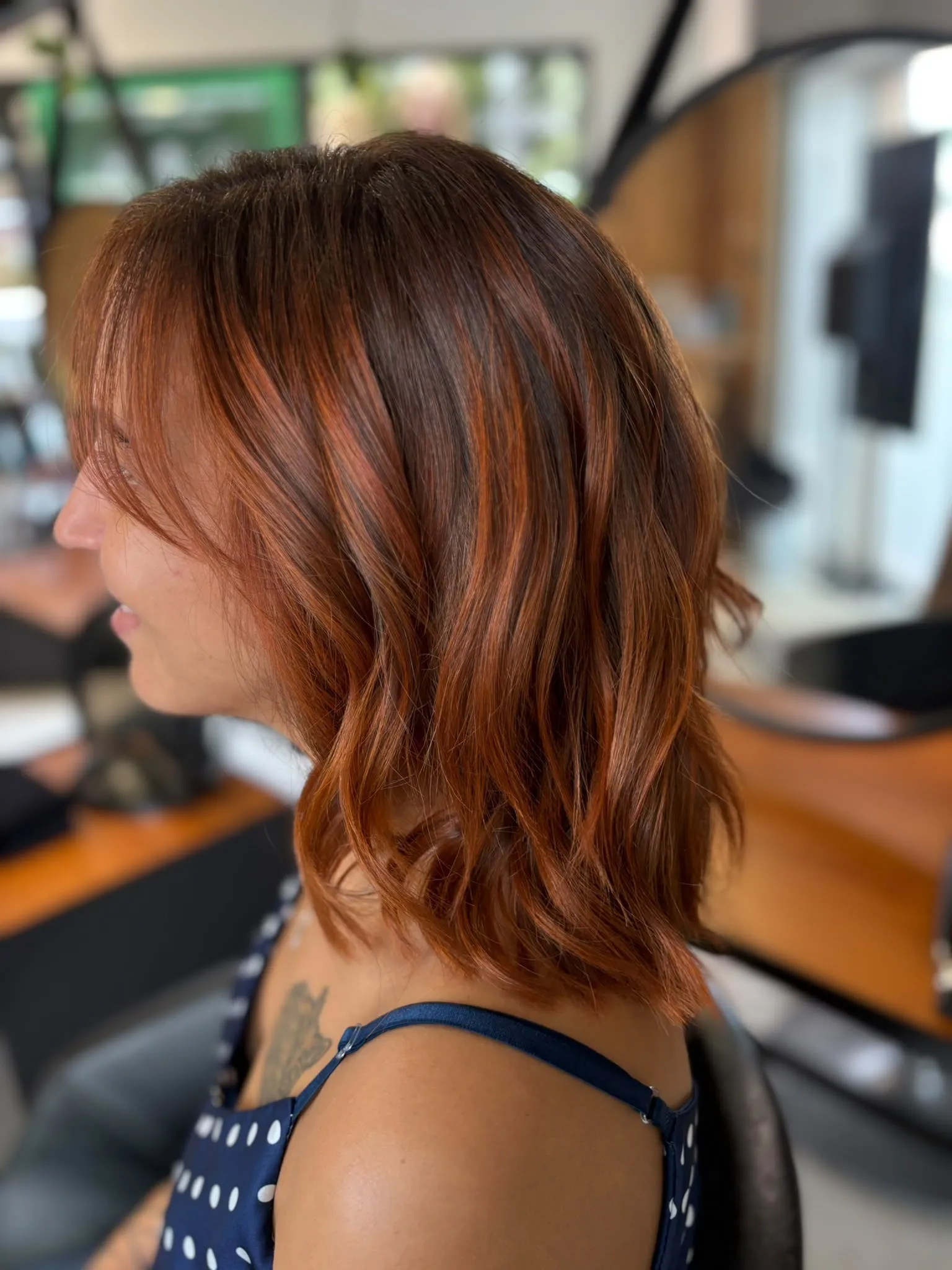 Profil d’une femme souriante aux cheveux mi-longs roux cuivré avec frange légère