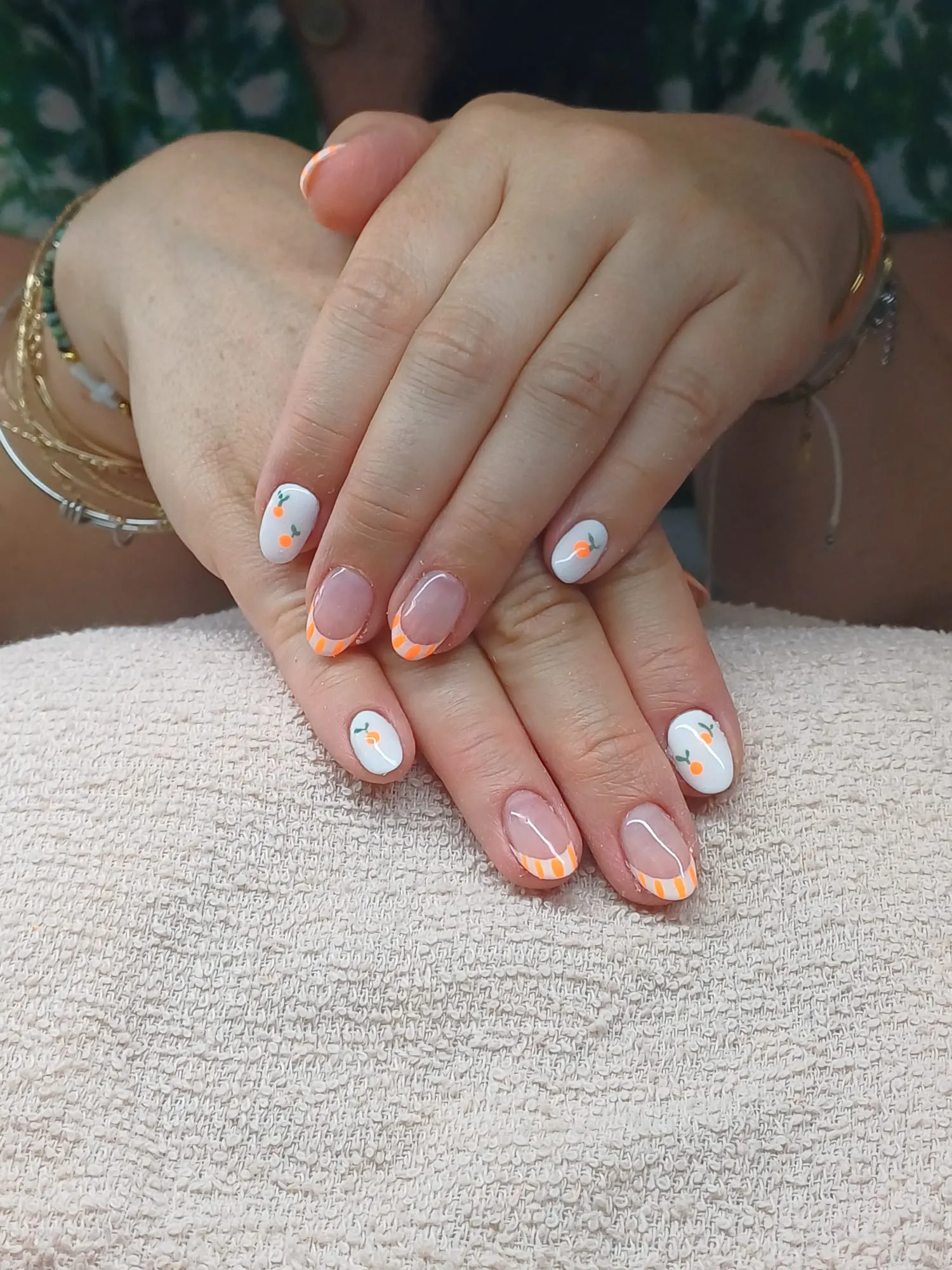 Ongles arrondis décorés de motifs d’agrumes orange et de touches vertes