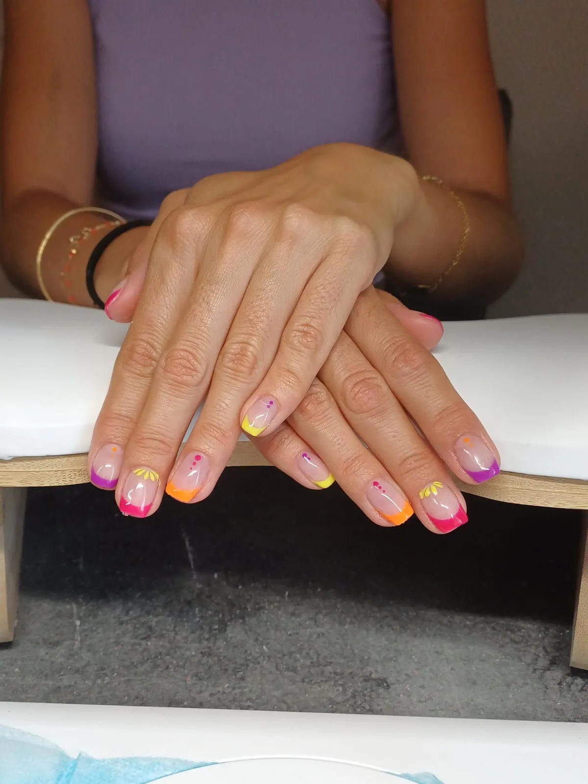 Mains avec des ongles longs aux pointes colorées et aux motifs floraux