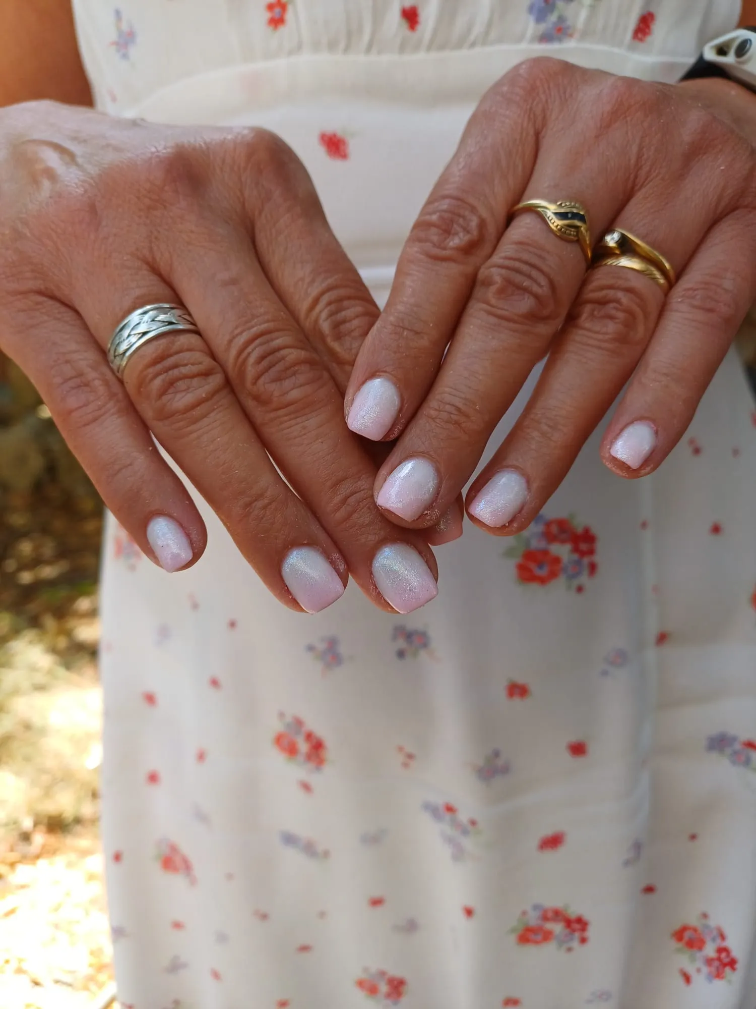 Mains aux ongles courts rose pâle nacré avec des bagues